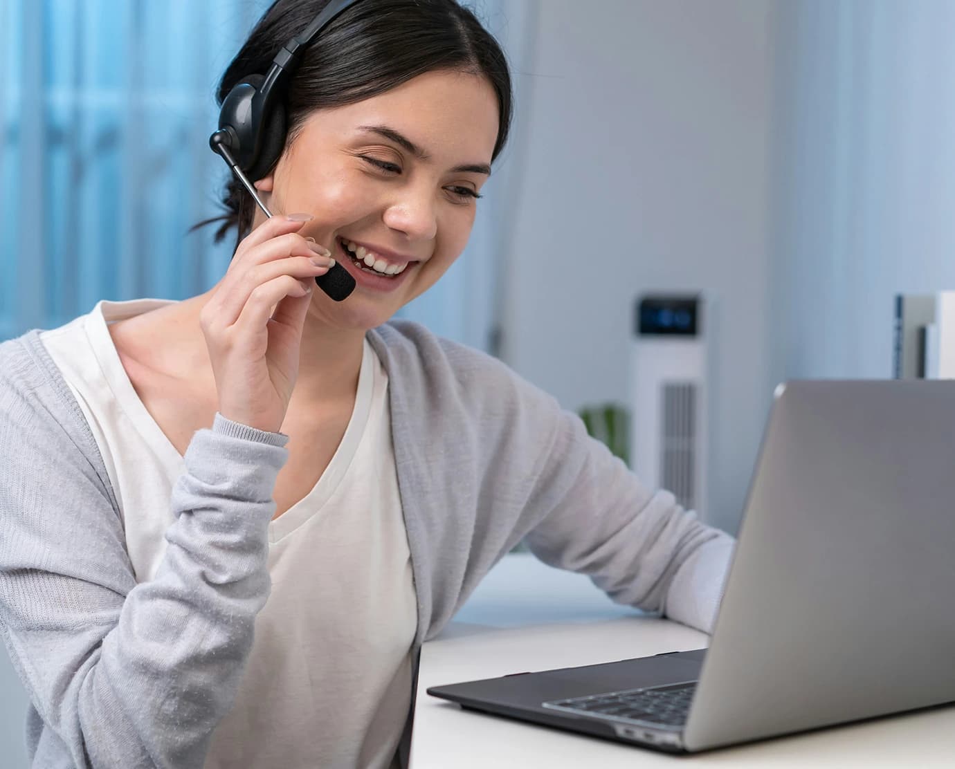 An Educbank support agent wearing a headset and smiling while working at a laptop