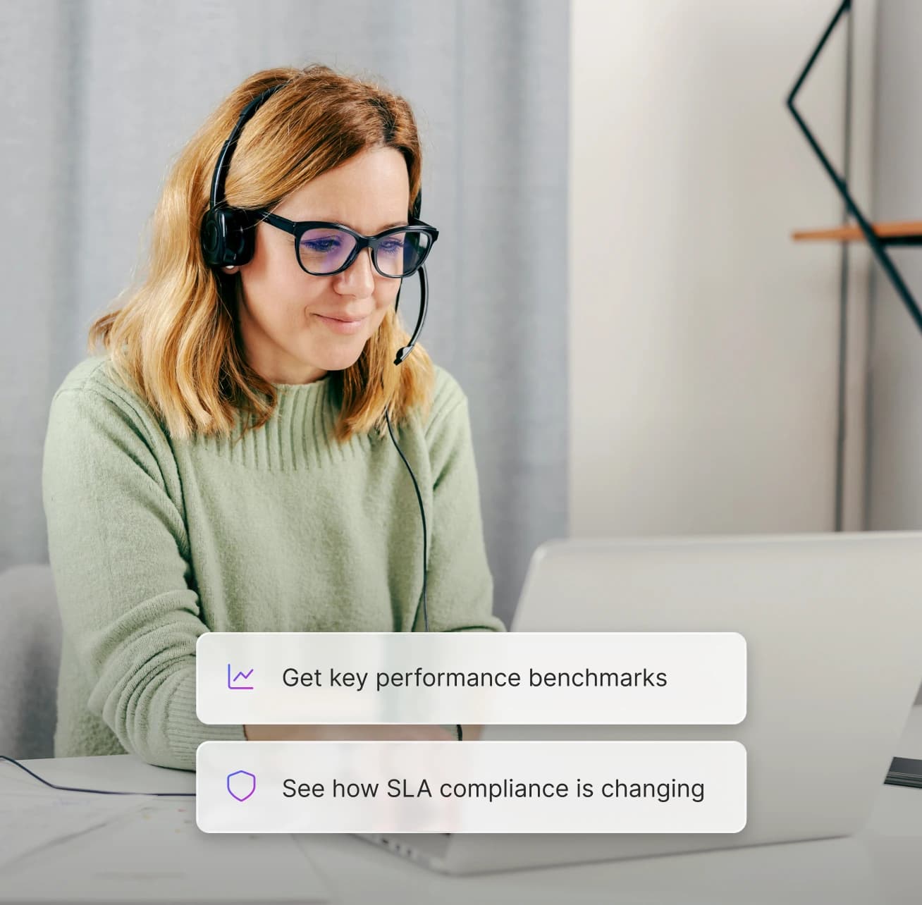A support rep wearing a headset reviewing performance benchmarks and SLA compliance on a laptop