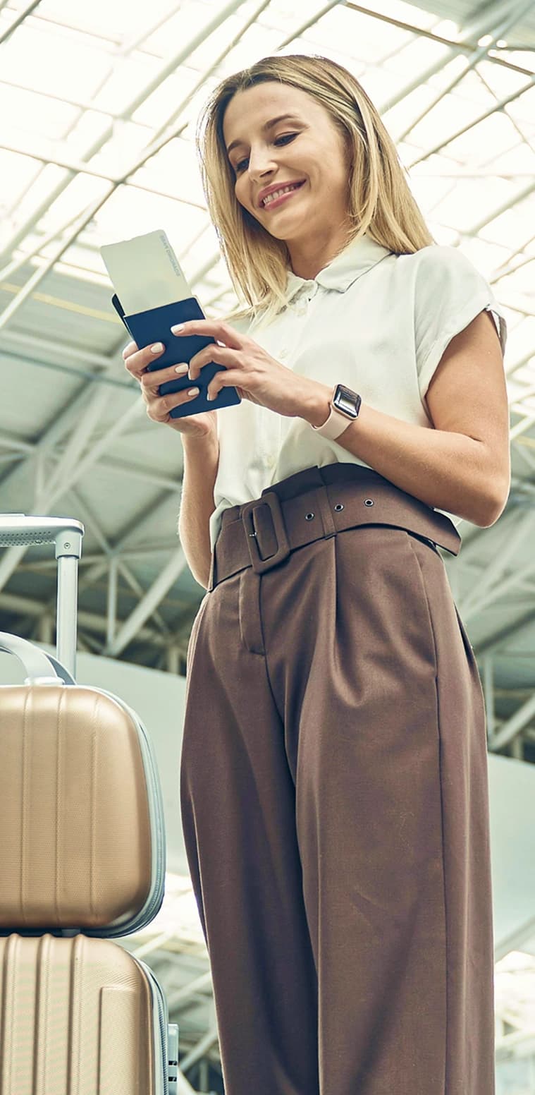 A traveler checking her passport and phone next to her luggage in an airport