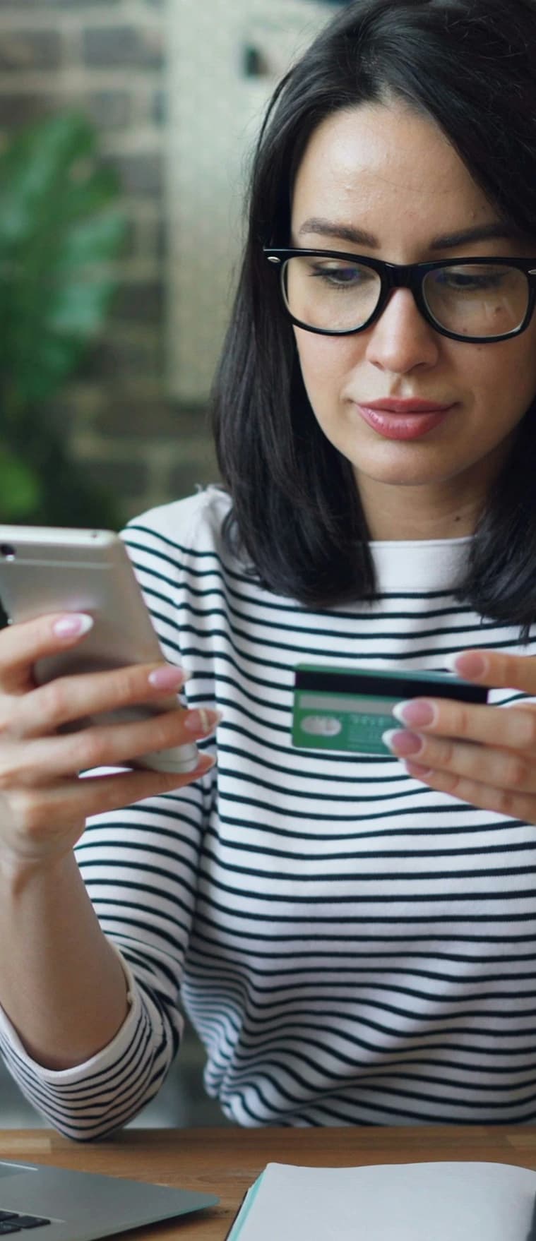 A customer shopping online, holding a credit card and a phone