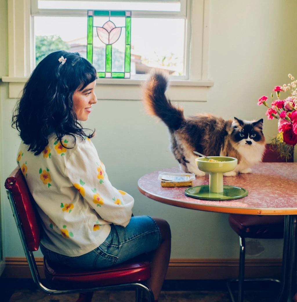Girl sitting at table with cat on table